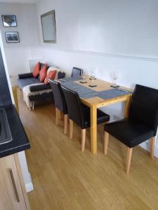 mesa de comedor con sillas negras y sofá en 2 Bed pet-free cottage, private garden & fell view, en Arlecdon