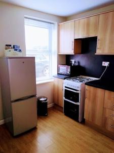 a small kitchen with a stove and a refrigerator at 2 Bed pet-free cottage, private garden & fell view in Arlecdon