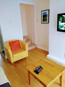 a living room with a yellow chair and a coffee table at 2 Bed pet-free cottage, private garden & fell view in Arlecdon