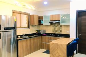 cocina con armarios de madera y nevera de acero inoxidable en 03-JenVin Luxury Homes - Garden view 2bed Apartment North Goa, en Old Goa