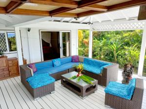 une terrasse couverte avec un canapé bleu, des chaises et une table dans l'établissement Villa MERAHI ... La villa d'Ange Fare Noa Mymy, à Uturoa