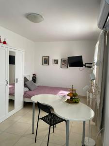 uma mesa branca e cadeiras num quarto com uma cama em my holiday apartment em Zikhron Ya‘aqov