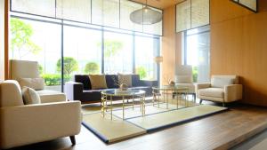 a living room with couches and tables and windows at Hotel Osaka PIK2 in Tangerang