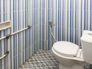ein Badezimmer mit Toilette und einer blau-weiß gestreiften Wand in der Unterkunft Johje Guest House Medan Mitra RedDoorz in Medan