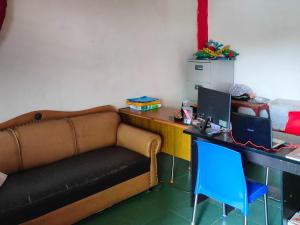 Zimmer mit einem Sofa und einem Schreibtisch mit einem Computer in der Unterkunft Johje Guest House Medan Mitra RedDoorz in Medan