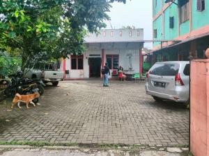 ein Mann und ein Hund gehen auf einer gepflasterten Straße in der Unterkunft Johje Guest House Medan Mitra RedDoorz in Medan