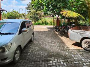 ein Minivan, der neben einem Motorrad und einem Auto geparkt ist in der Unterkunft Johje Guest House Medan Mitra RedDoorz in Medan