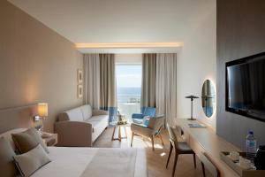 a hotel room with a living room with a bed and a television at Mediterranean Beach Hotel in Limassol