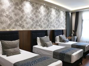 een hotelkamer met 2 bedden en een muur bij GRAND ÜSKÜDAR OTEL in Istanbul
