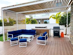 a patio with a blue couch and chairs and a grill at Villa utopia in Paphos City