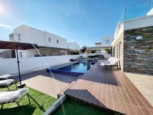 a backyard with a swimming pool and some chairs and an umbrella at Villa utopia in Paphos City