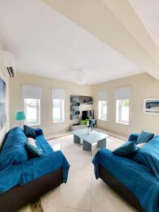 a living room with a blue couch and a table at Villa utopia in Paphos City