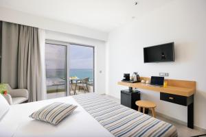 a hotel room with a bed and a desk with a laptop at Batis Beach Hotel in Rethymno Town