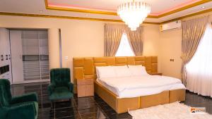 ein Schlafzimmer mit einem großen Bett und zwei grünen Stühlen in der Unterkunft Zackai Executive Guest house in Mlichakpo