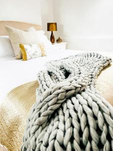 a white bedroom with a large blanket on a bed at Pen Y Bont Cottage in Llanuwchllyn