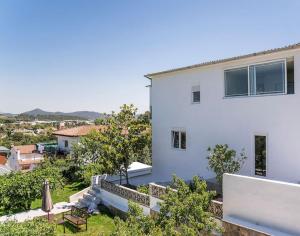 a white house with a view of a yard at 20 min from BCN- Charming house w/ pool & BBQ area in Cervelló