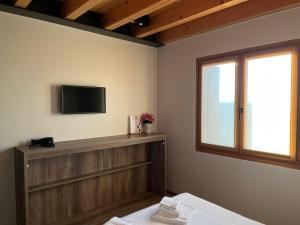 Habitación con TV, cama y ventana. en B&B Il Vigneto, en Desenzano del Garda
