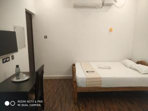 a bedroom with a bed and a table and a tv at BlueMoon Homestay in Puducherry