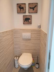 une salle de bains avec toilettes et trois photos sur le mur. dans l'établissement TERRASSES DE MALMEDY - Duplex "HAPPINESS" - Pellet & Airco-, à Malmedy 54 autres photos