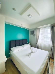 a bedroom with a large white bed with a blue wall at Functional 1-br Space in Amaia with Fast Internet in Mandaue City