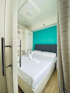 białe łóżko w pokoju z niebieską ścianą w obiekcie Functional 1-br Space in Amaia with Fast Internet w mieście Mandaue City