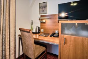 a hotel room with a desk with a television and a chair at Hotel Haus Berlin in Bonn