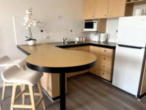 een keuken met een tafel en een witte koelkast bij Ocean Views - Top floor in Alexandra Headland