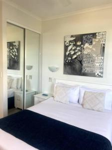 een slaapkamer met een wit bed en een grote spiegel bij Ocean Views - Top floor in Alexandra Headland