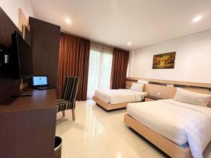 a hotel room with two beds and a desk at Lembah Permai Resort in Sindanglaya