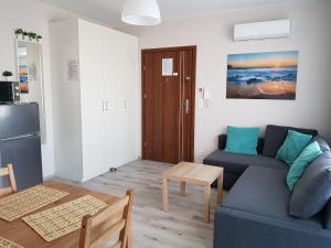 a living room with a blue couch and a table at Apartament na Zaciszu in Kąty Rybackie