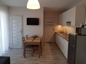 a kitchen with a wooden table and a kitchen with a refrigerator at Apartament na Zaciszu in Kąty Rybackie