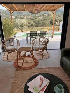 a living room with a table and chairs and a patio at Casa Agatha : Villa avec piscine in Figari