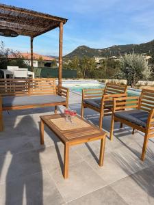 a patio with wooden tables and chairs and a pool at Casa Agatha : Villa avec piscine in Figari