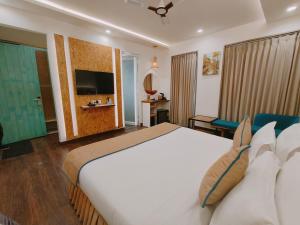Cette chambre comprend un grand lit et une télévision. dans l'établissement Ataraxia Crestmont Resort & Spa, à Dehradun