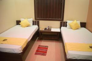 two beds in a small room with a table at Hotel Shakuntla Palace in Gaya