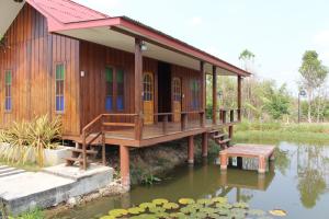 a house on the water next to a pond at OYO 75419 Baan Suan Mulberry Farmstay in Hua Hin