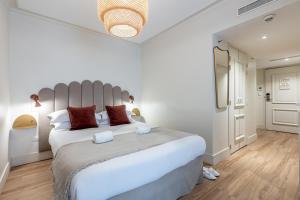 um quarto branco com uma grande cama branca com almofadas vermelhas em Le Nest by Sweet Inn em Paris