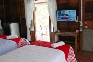 a bedroom with two beds and a tv and a window at OYO 75419 Baan Suan Mulberry Farmstay in Hua Hin