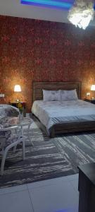 1 dormitorio con cama y pared roja en بوابة الرمال السياحية Tourism sands gate en Al Wāşil