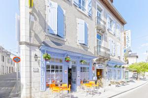 a building with yellow tables and chairs on a street at Logis Hôtel de France in Arudy