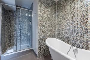 巴黎的住宿－Le Nest by Sweet Inn，带浴缸和玻璃淋浴间的浴室。