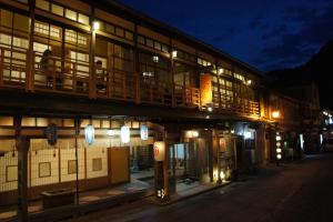天川村的住宿－花屋徳兵衛旅館，一座晚上有人坐在阳台上的建筑