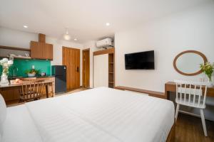 a bedroom with a white bed and a kitchen at Samatha Apartment & Hotel in Da Nang