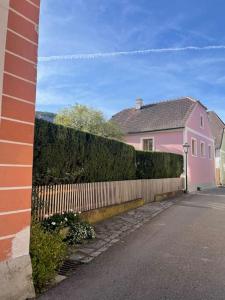 ein rosa Haus mit einem Zaun neben einem Haus in der Unterkunft Altes Winzerhaus in der Wachau - neu renoviertes Haus mit Terrasse in Dürnstein