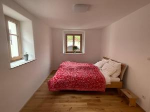 1 Schlafzimmer mit einem Bett mit einer roten Decke und 2 Fenstern in der Unterkunft Altes Winzerhaus in der Wachau - neu renoviertes Haus mit Terrasse in Dürnstein