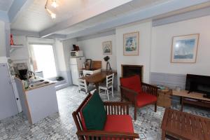 la petite maison du Portrieux في سان-كواي-بورتريو: مطبخ وغرفة معيشة مع كراسي حمراء وثلاجة