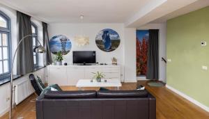 een woonkamer met een bank en een tv bij Appartement La Charrette in Tilburg
