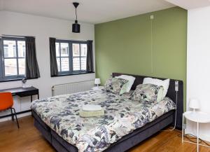 a bedroom with a bed and a desk and windows at Appartement La Charrette in Tilburg