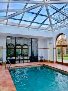 une grande piscine avec un plafond en verre dans l'établissement Maison Suchard, tradition & elegance in the Jura, à Couvet