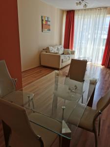 uma sala de estar com uma mesa de vidro e cadeiras em Private Apartment in Golden Sands - Aquamarine Odessos em Golden Sands